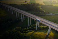 Truck on a high bridge crossing lands of green